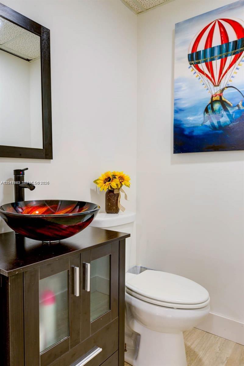 A bathroom features a dark wood vanity, a red glass vessel sink, and wall art — 12349 SW 132nd Ct # 9, Miami FL 33186, MIAMI, FL