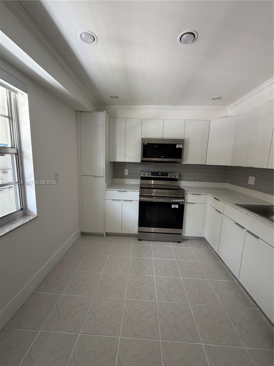 A kitchen features white flat-panel cabinets, stainless steel appliances, and light gray tiled flooring — 4007 N Cypress Dr # 203, Pompano Beach FL 33069, POMPANO BEACH, FL