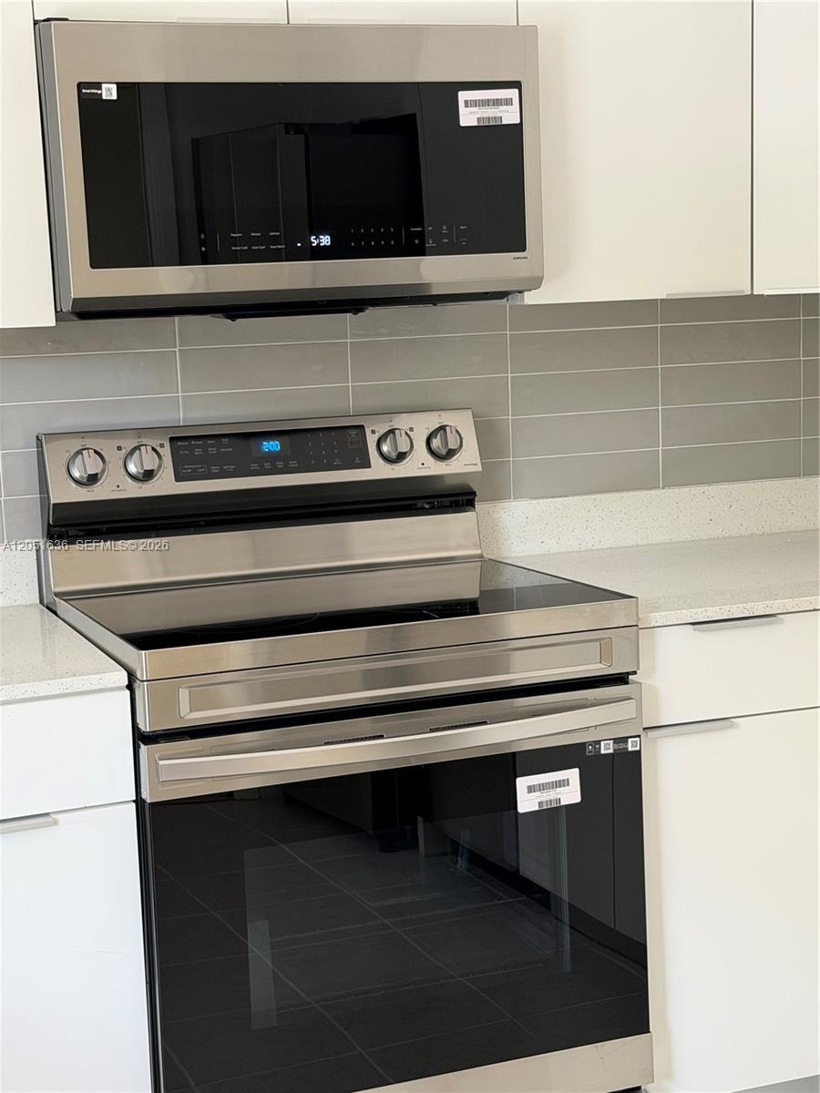 A stainless steel microwave and electric range are installed in a kitchen with white cabinets — 4007 N Cypress Dr # 203, Pompano Beach FL 33069, POMPANO BEACH, FL