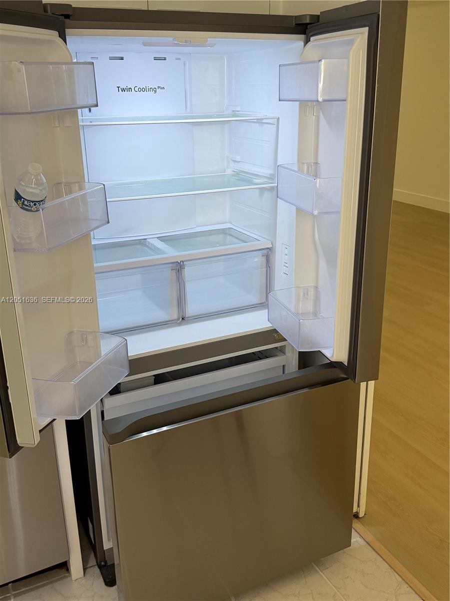An open stainless steel refrigerator with glass shelves and door bins stands in a kitchen — 4007 N Cypress Dr # 203, Pompano Beach FL 33069, POMPANO BEACH, FL