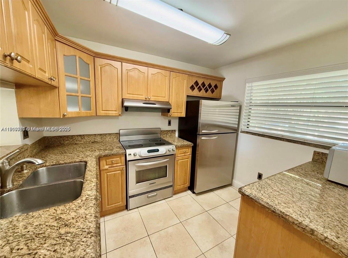 A kitchen features light wood cabinets, granite countertops, stainless steel appliances, and tile flooring — 10825 SW 112th Ave # 302, Miami FL 33176, MIAMI, FL