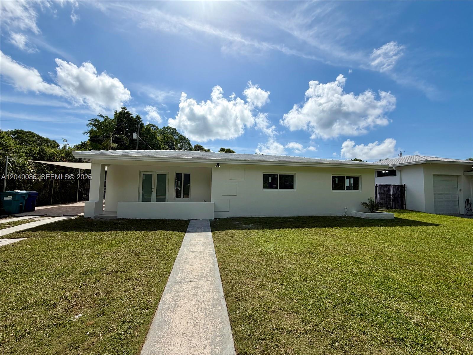 A single-story white house with a concrete walkway and a green lawn under blue skies — 8235 SW 62nd Pl, Miami FL 33143, MIAMI, FL