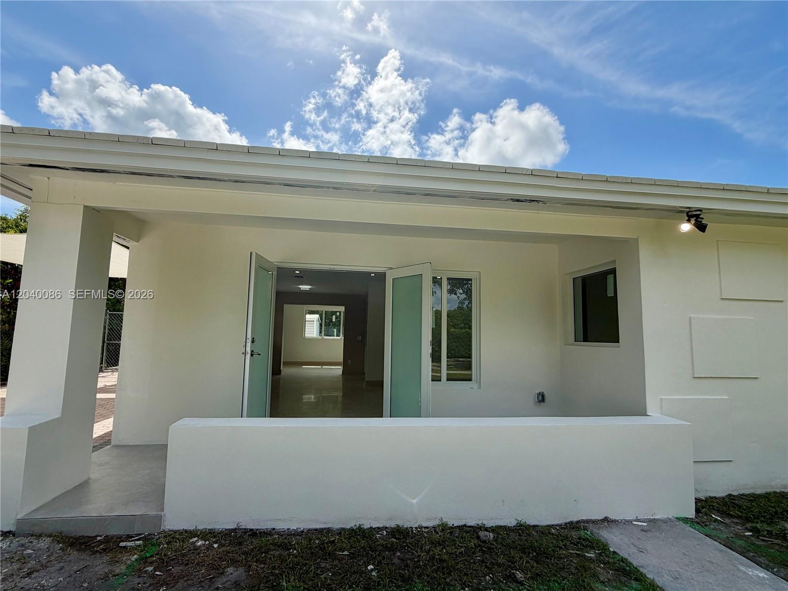 A white exterior patio features a low wall, double glass doors, and a small window — 8235 SW 62nd Pl, Miami FL 33143, MIAMI, FL