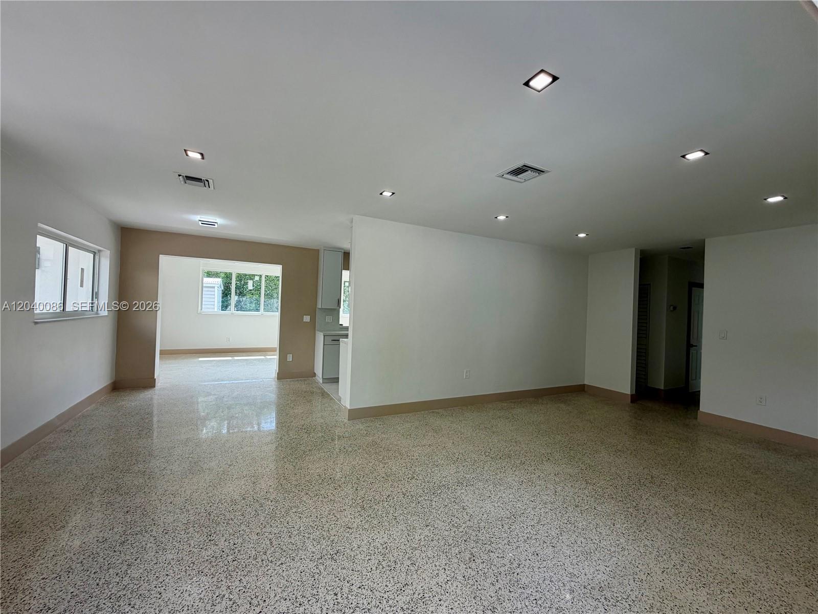 An open-concept living area features terrazzo flooring, recessed lighting, and a view into a kitchen — 8235 SW 62nd Pl, Miami FL 33143, MIAMI, FL