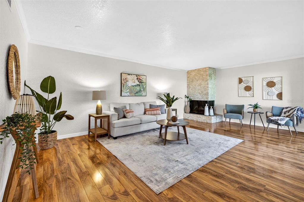 A living room features hardwood floors, a stone fireplace, and a neutral sofa with area rug — 9342 TRADEWINDS AVENUE, SEMINOLE, FL