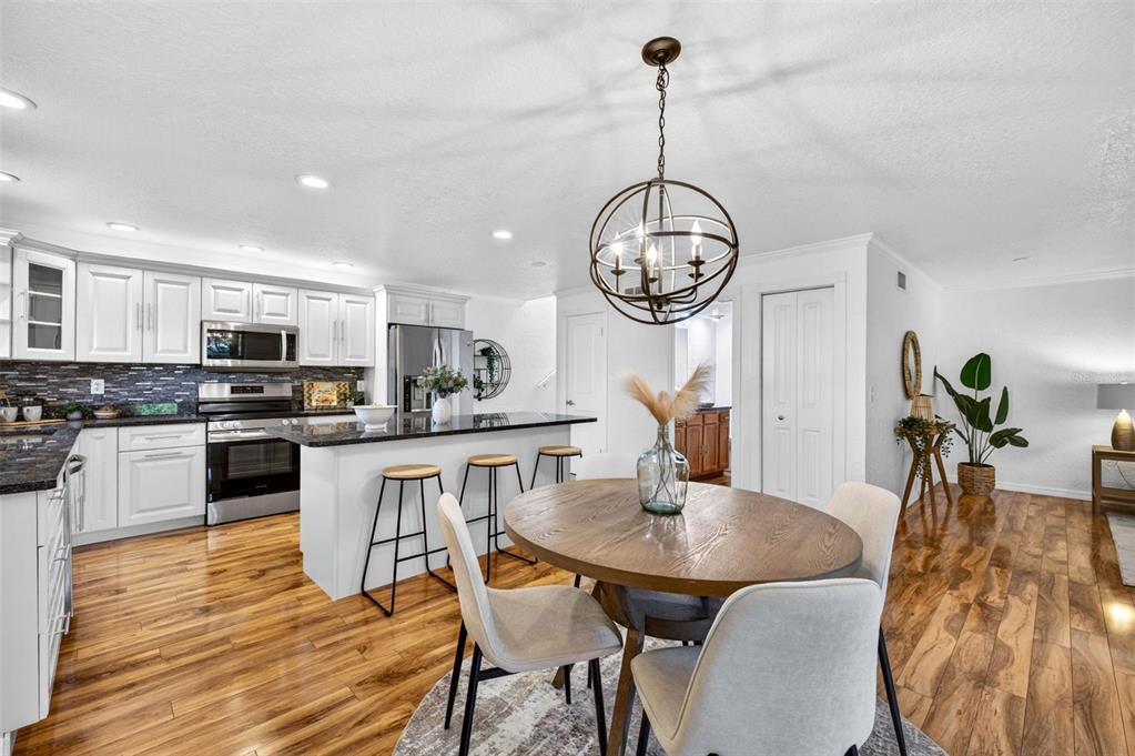 A kitchen and dining area with white cabinets, a dark island, and wood flooring — 9342 TRADEWINDS AVENUE, SEMINOLE, FL