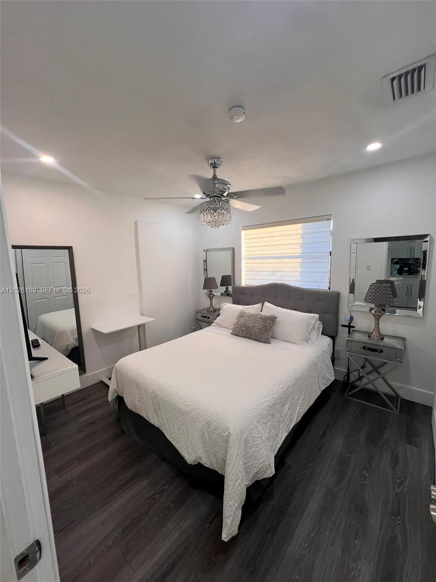 A bedroom features a bed with a gray headboard, dark wood flooring, and mirrored accents — 3411 SW 121st Ave, Miami FL 33175, MIAMI, FL