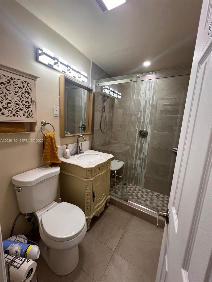 A bathroom features a toilet, a vanity with a stone top, and a glass shower — 3411 SW 121st Ave, Miami FL 33175, MIAMI, FL