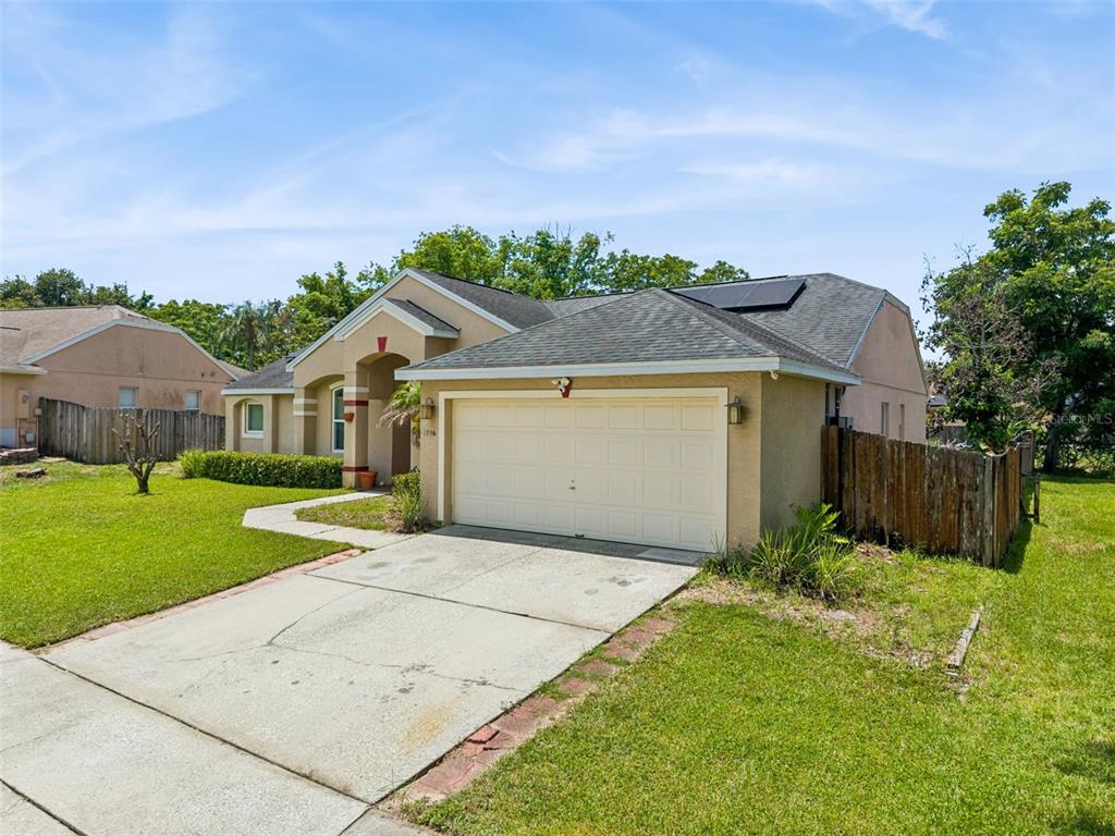 A tan single-story house with a two-car garage, a concrete driveway, and a shingled roof — 1796 FLORENCE VISTA BOULEVARD, ORLANDO, FL