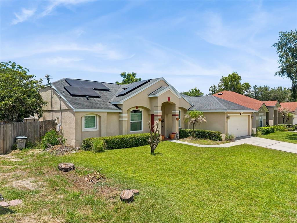 A single-story house with a tan stucco exterior, solar panels, and a two-car garage — 1796 FLORENCE VISTA BOULEVARD, ORLANDO, FL
