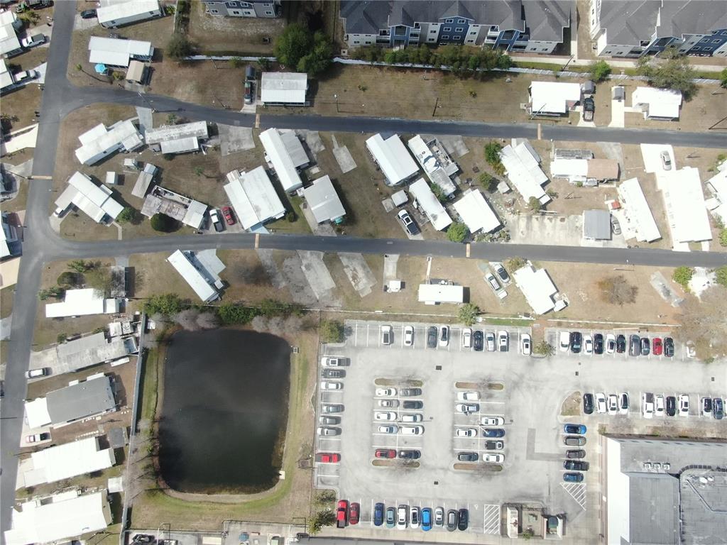 This aerial view shows a residential neighborhood with mobile homes, a pond, and parking lots — 6720 PARK BOULEVARD N UNIT 20, PINELLAS PARK, FL