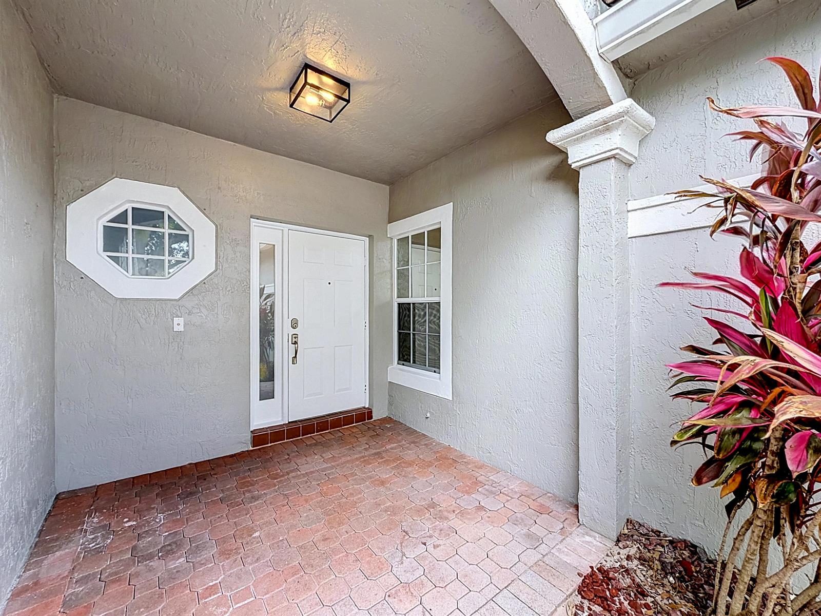 A covered entryway features a white front door, an octagonal window, and brick flooring — 8279 Via Leonessa Drive, Boca Raton FL 33433, BOCA RATON, FL