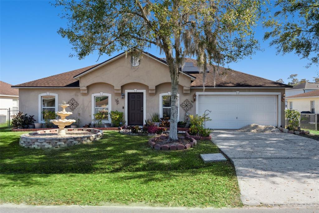 A single-story house with a beige stucco exterior, a two-car garage, and a front fountain — 907 SALERNO COURT, KISSIMMEE, FL