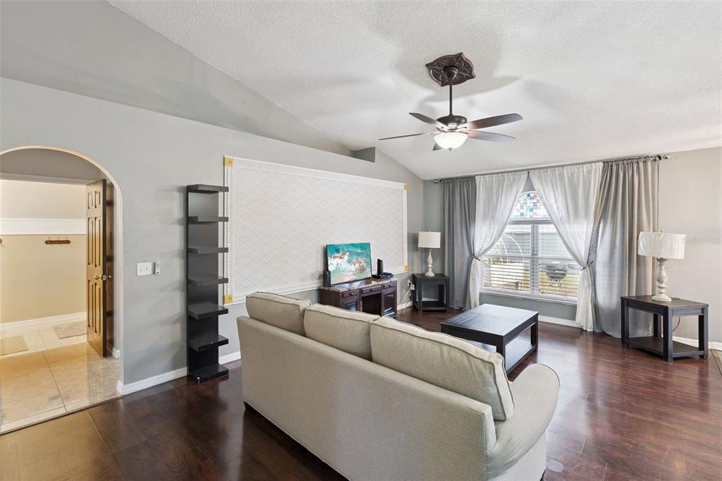 A living room features a beige sofa, dark wood floors, and a large decorative wall panel — 907 SALERNO COURT, KISSIMMEE, FL