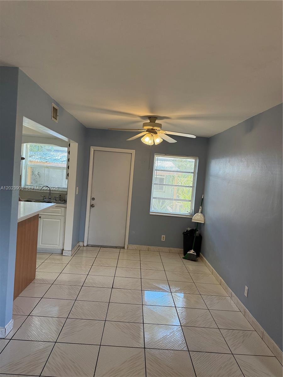 A dining area features light blue walls, white tile flooring, a ceiling fan, and a window — 3525 Polk St # 7, Hollywood FL 33021, HOLLYWOOD, FL