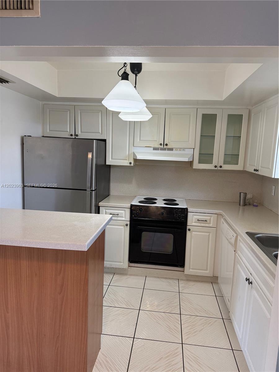 A kitchen features white cabinets, stainless steel appliances, a black stove, and tiled flooring — 3525 Polk St # 7, Hollywood FL 33021, HOLLYWOOD, FL