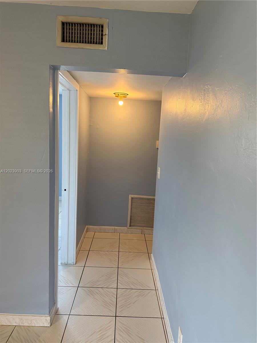 A hallway with light blue walls, tiled flooring, and a ceiling light fixture — 3525 Polk St # 7, Hollywood FL 33021, HOLLYWOOD, FL