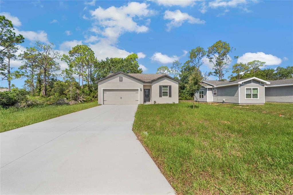A single-story house with a two-car garage and a concrete driveway under a blue sky — 1306 CONGO COURT, POINCIANA, FL