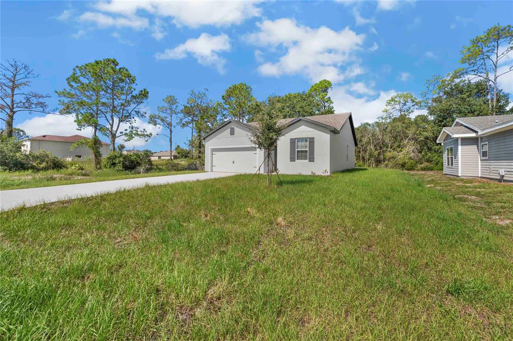 A single-story house with a garage and a concrete driveway sits on a grassy lot — 1306 CONGO COURT, POINCIANA, FL