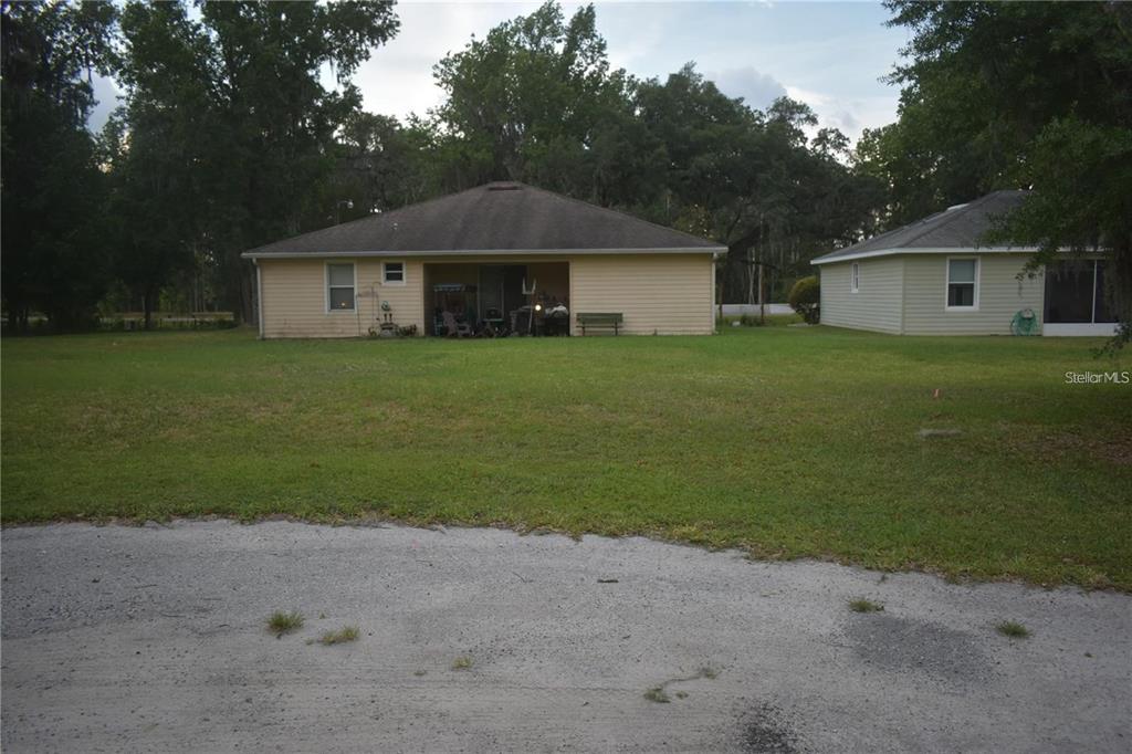 A view of the back of two single-story houses with a large grassy yard — LOT 25 BLK D STRATFORD COURT, WILDWOOD, FL