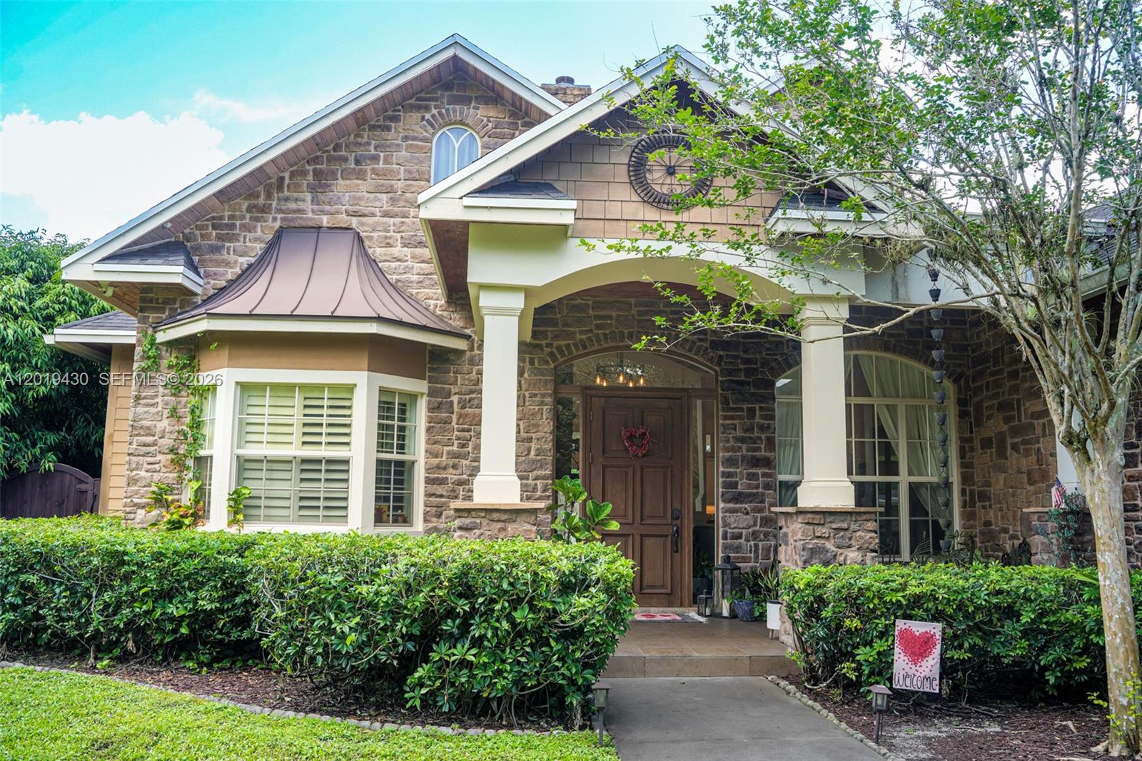 A stone-clad house exterior features a covered entryway, a bay window, and a front garden — 2640 SW 137th Ter, Davie FL 33330, DAVIE, FL