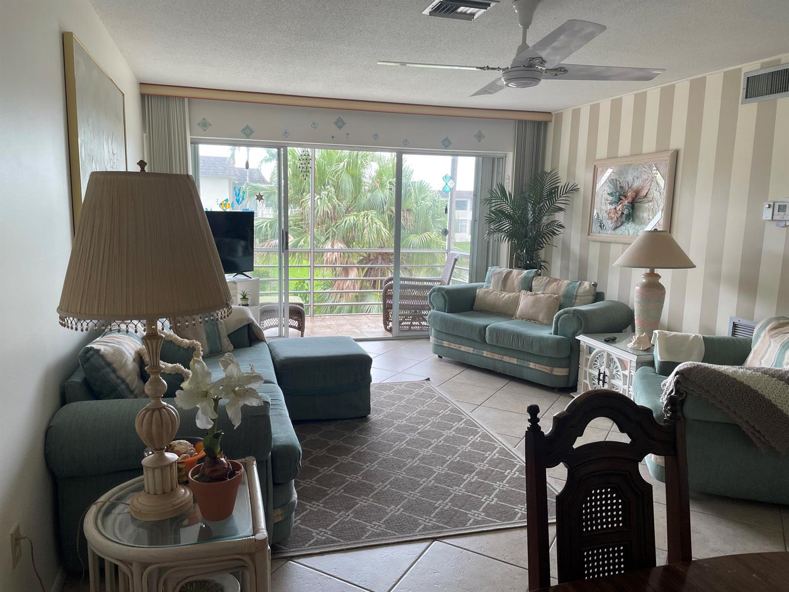 A living room features teal sofas, a patterned area rug, and a sliding glass door — 506 Davis Road # 78, Palm Springs FL 33461, PALM SPRINGS, FL