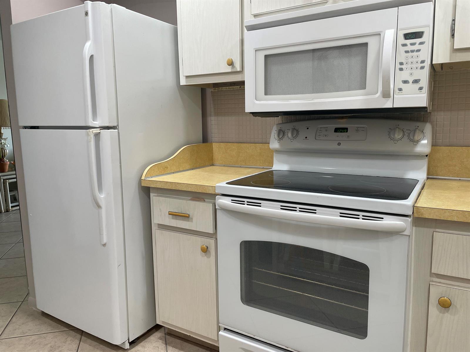 A kitchen features white appliances, light wood cabinets, and yellow laminate countertops — 506 Davis Road # 78, Palm Springs FL 33461, PALM SPRINGS, FL