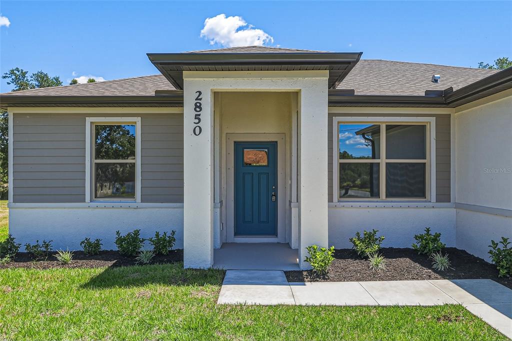The exterior of a single-story house features a teal front door and horizontal siding — 2850 ESCAMBIA CIRCLE, NORTH PORT, FL