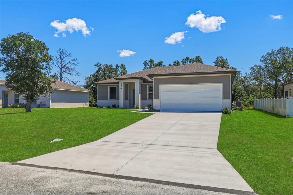 A single-story house with a white garage door and a concrete driveway sits on grass — 2850 ESCAMBIA CIRCLE, NORTH PORT, FL