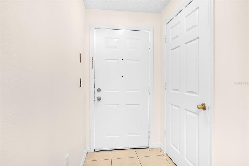 An entryway features a white front door, a white interior door, and light-colored floor tiles — 10873 WINDSOR WALK DRIVE UNIT 4106, ORLANDO, FL