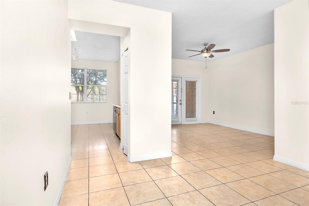 An interior view shows a tiled living area and a kitchen with a window — 10873 WINDSOR WALK DRIVE UNIT 4106, ORLANDO, FL