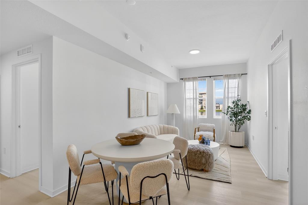 A bright, modern living and dining area features light wood floors, white walls, and furniture — 5579 MILLENIA PARK BOULEVARD UNIT 101, ORLANDO, FL