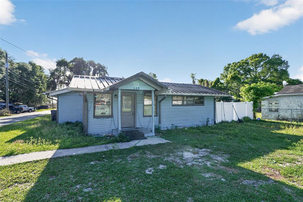 A single-story house with light blue siding, a metal roof, and a front porch — 108 EARL AVENUE, AUBURNDALE, FL