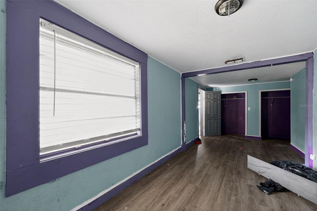 A room with light blue walls, purple trim, wood-look flooring, and two open closets — 108 EARL AVENUE, AUBURNDALE, FL