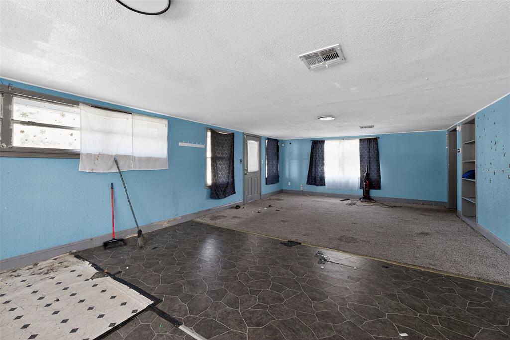 A living room with blue walls, a mix of tile and carpet flooring, and windows — 108 EARL AVENUE, AUBURNDALE, FL