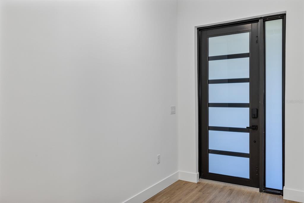 A modern front door with frosted glass panels sits next to a plain white wall — 493 SYCAMORE, PORT CHARLOTTE, FL