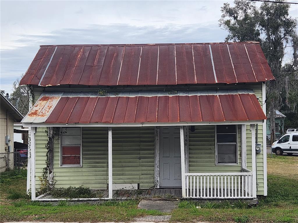 A small, light green house with a rusted metal roof and a front porch — 11760 N WILLIAMS STREET, DUNNELLON, FL