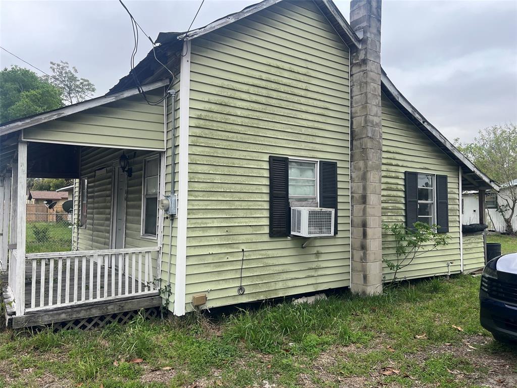 A side view of a pale green, single-story house with a porch and a chimney — 11760 N WILLIAMS STREET, DUNNELLON, FL