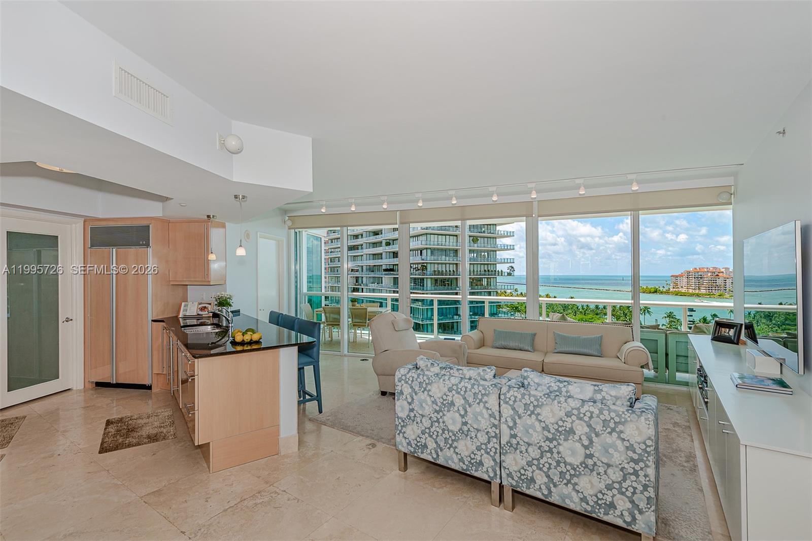 An open-concept living area features a kitchen with light wood cabinets and ocean views — 1000 S Pointe Drive # 905, Miami Beach FL 33139, MIAMI BEACH, FL
