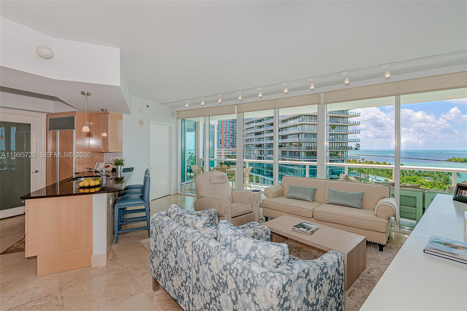 A living room and kitchen area feature floor-to-ceiling windows with ocean and city views — 1000 S Pointe Drive # 905, Miami Beach FL 33139, MIAMI BEACH, FL