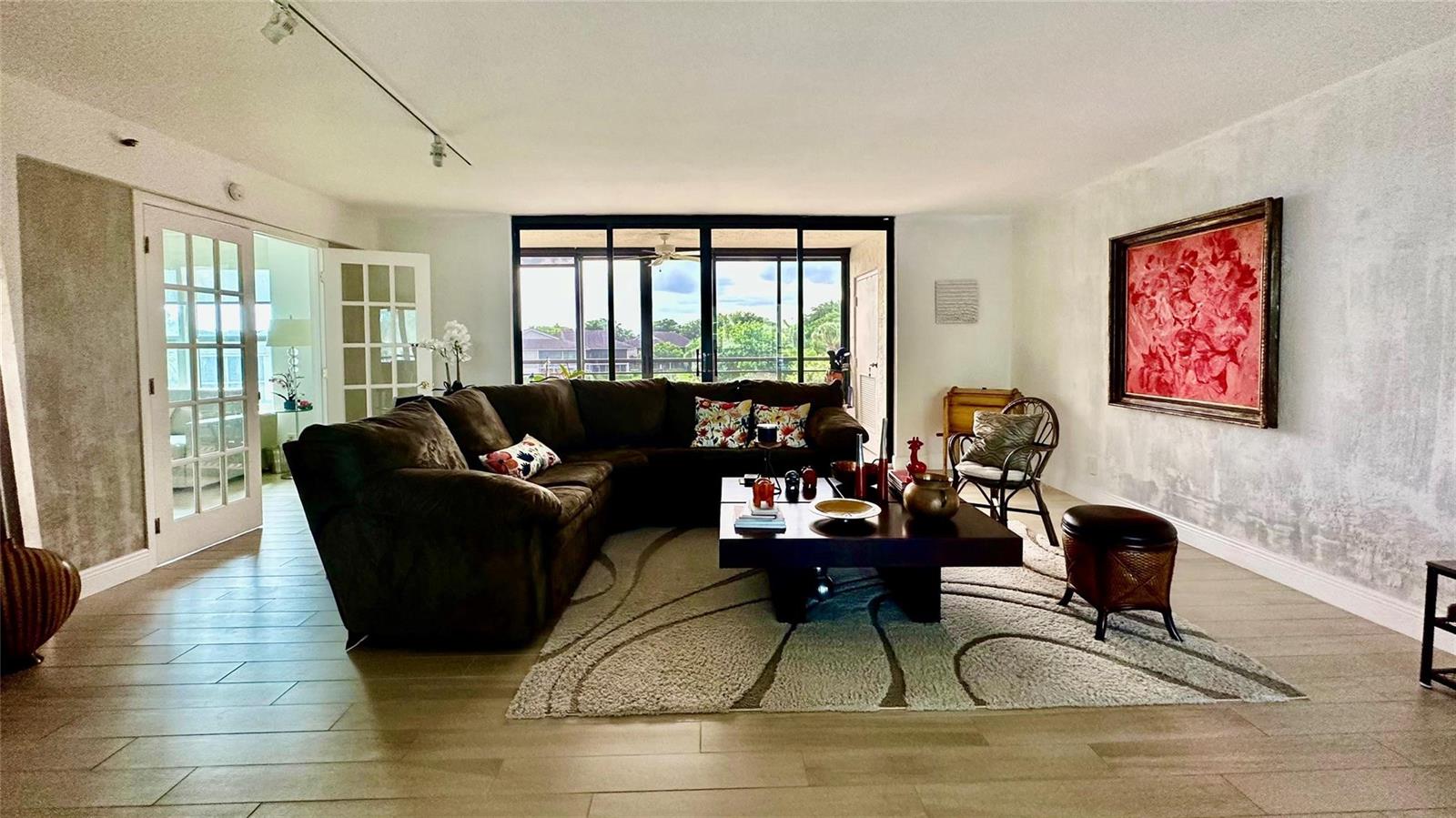 A living room features a large brown sectional, a coffee table, and a red painting — 7582 Regency Lake Drive, Boca Raton FL 33433, BOCA RATON, FL