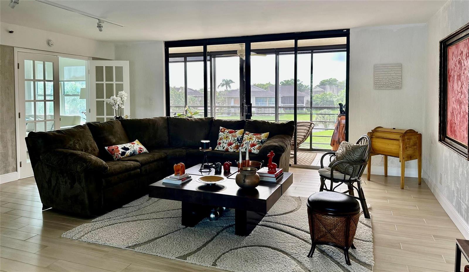 A living room with a large brown sectional, dark coffee table, and sliding glass doors — 7582 Regency Lake Drive, Boca Raton FL 33433, BOCA RATON, FL