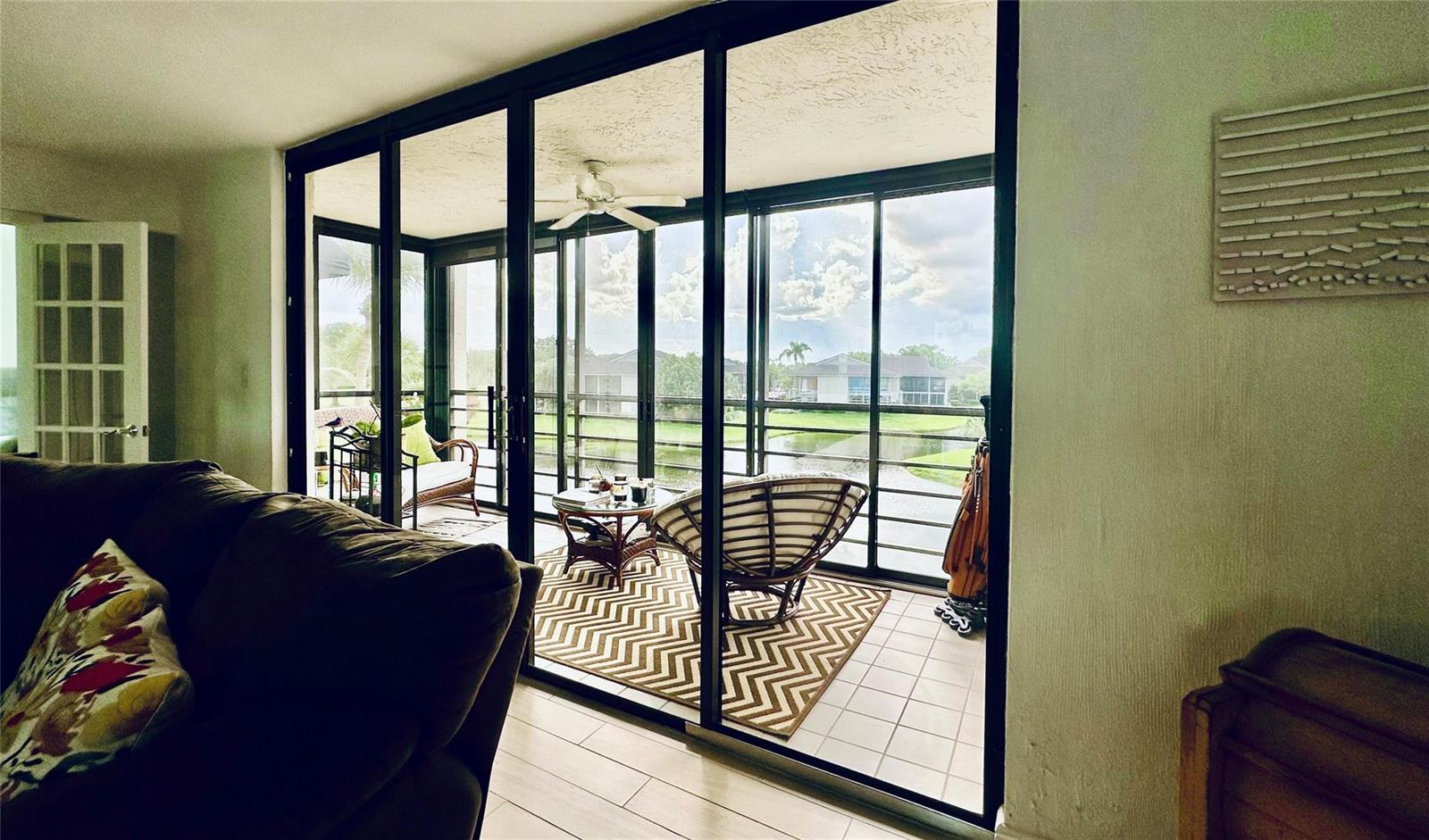 A living room looks out through large sliding glass doors onto a screened-in patio — 7582 Regency Lake Drive, Boca Raton FL 33433, BOCA RATON, FL