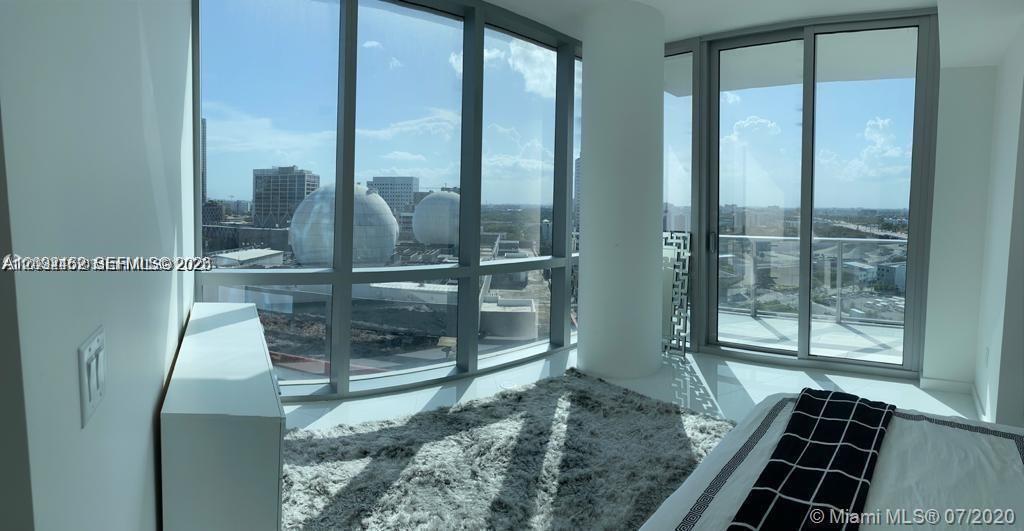 A bedroom features floor-to-ceiling windows with views of large spherical structures and city buildings — MIAMI, FL