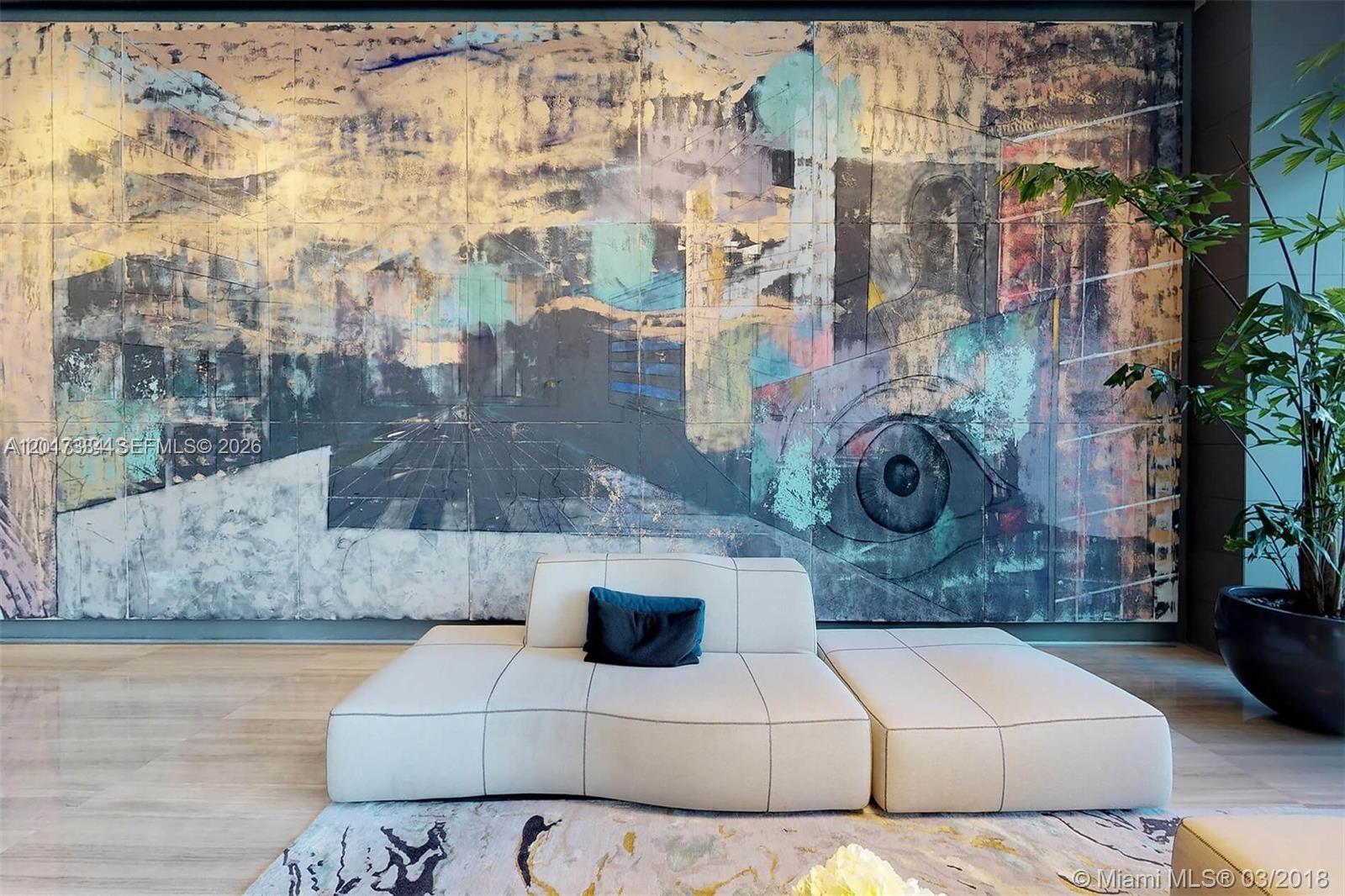 A modern lounge features a large abstract mural, a low white sofa, and a potted plant — 460 NE 28th ST # 1102, Miami FL 33132, MIAMI, FL