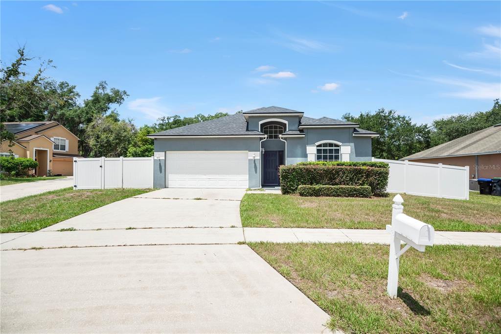 A single-story house with a gray exterior, a two-car garage, and a white fence — 7933 REX HILL TRAIL, ORLANDO, FL
