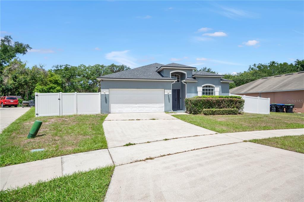 A single-story house with a gray exterior, a two-car garage, and a white vinyl fence — 7933 REX HILL TRAIL, ORLANDO, FL