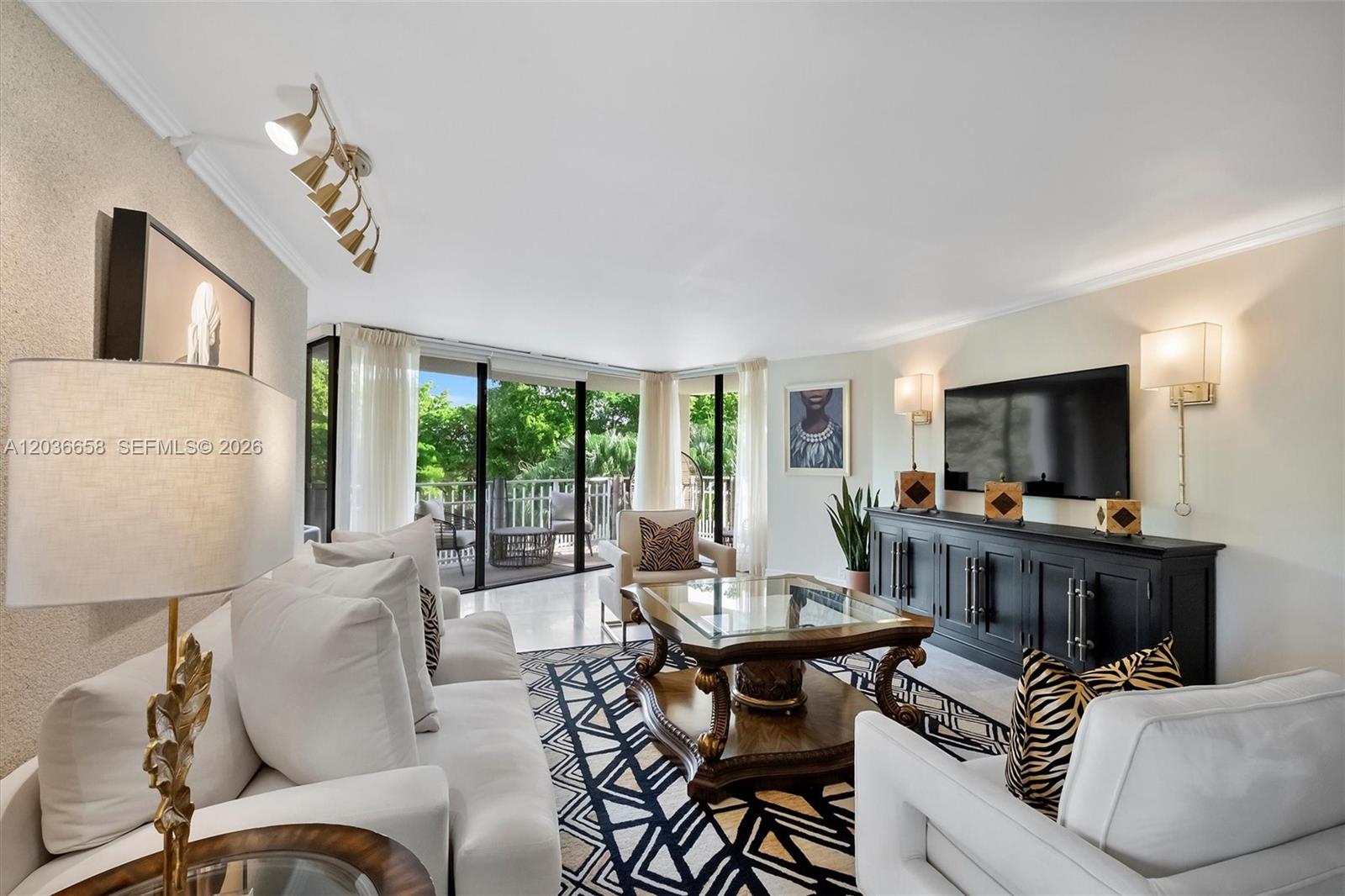 A bright living room features white sofas, a patterned rug, and a glass-topped coffee table — 1000 Quayside Ter # 411, Miami FL 33138, MIAMI, FL