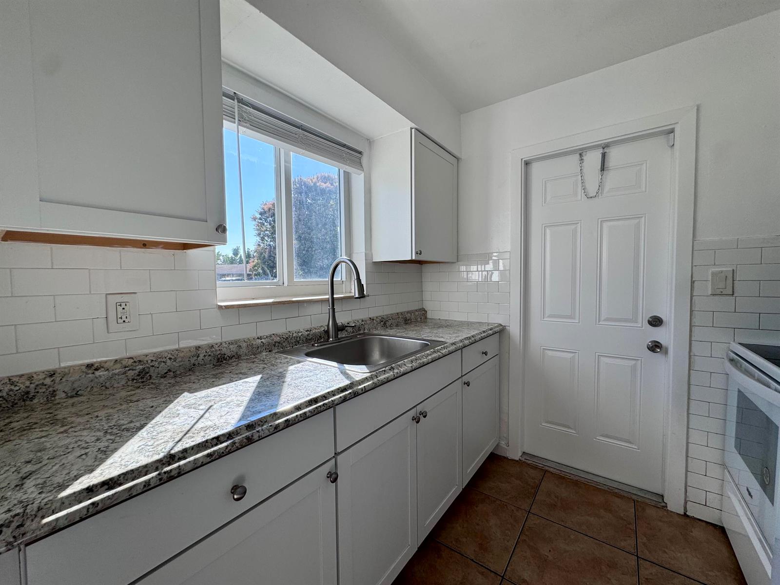 A kitchen features white cabinets, white appliances, a granite countertop, and a white subway tile backsplash — 3101 NE 7th Avenue # B, Pompano Beach FL 33064, POMPANO BEACH, FL