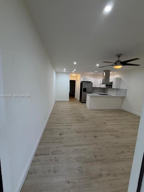 An open-concept kitchen and living area features light wood-look flooring and white cabinetry — 500 Layne Blvd # 19, Hallandale Beach FL 33009, HALLANDALE BEACH, FL